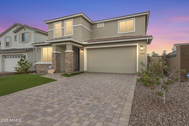view of front facade with stucco siding, decorative driveway, a garage, and fence