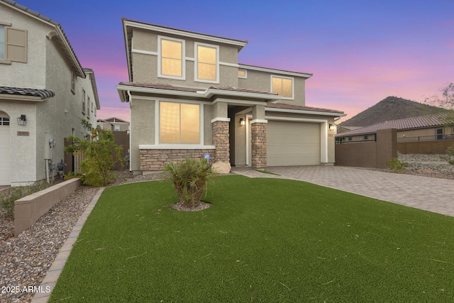 view of front facade with stucco siding, a lawn, decorative driveway, fence, and a garage