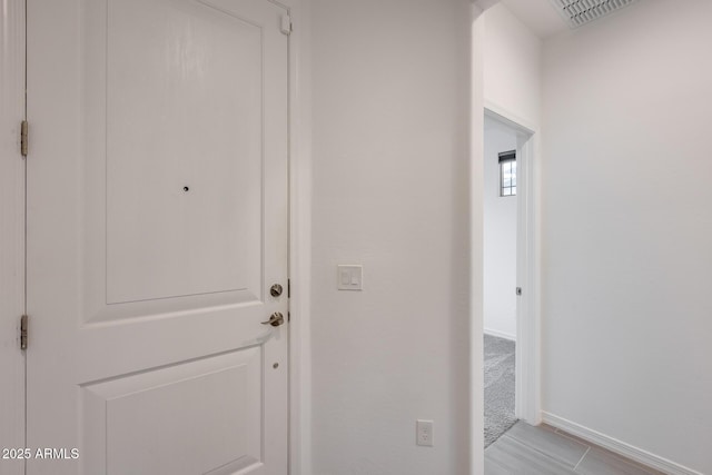 hallway featuring visible vents and baseboards