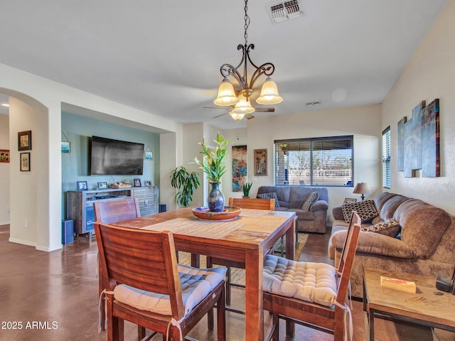 dining space with arched walkways, a notable chandelier, visible vents, concrete floors, and baseboards