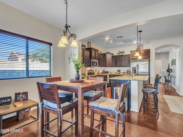 dining space with arched walkways and finished concrete flooring