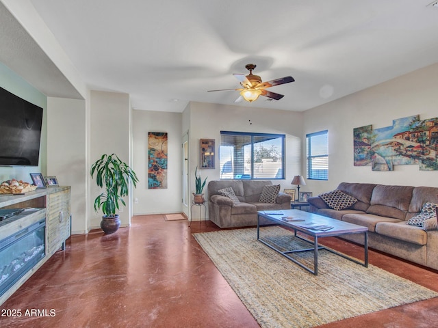 living area featuring baseboards, a ceiling fan, and concrete flooring