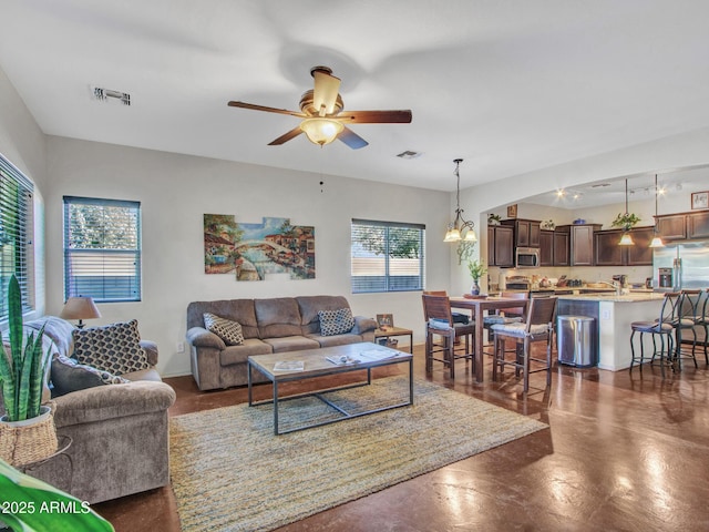 living room featuring visible vents, plenty of natural light, and ceiling fan with notable chandelier