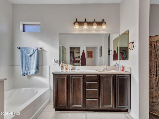 bathroom featuring double vanity, a garden tub, tile patterned flooring, a walk in closet, and a sink