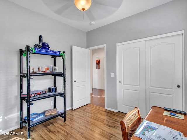 office space with light wood-type flooring, ceiling fan, and baseboards