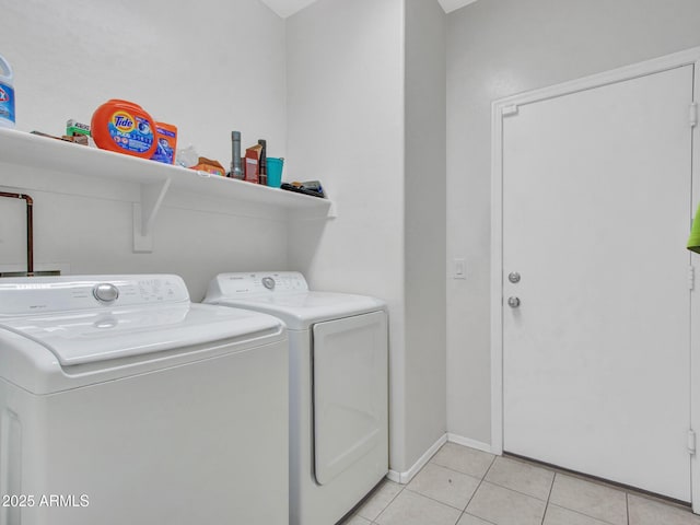 clothes washing area with washer and dryer, laundry area, baseboards, and light tile patterned floors