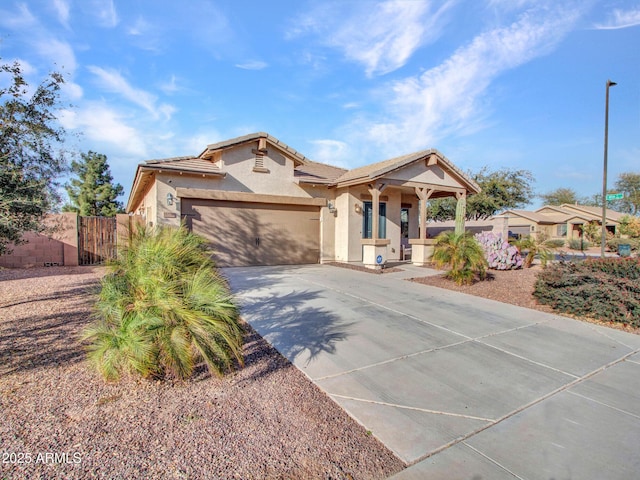 view of front facade featuring a garage, fence, concrete driveway, a tiled roof, and stucco siding