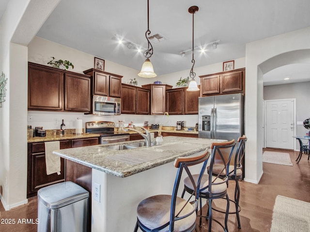 kitchen with arched walkways, visible vents, hanging light fixtures, stainless steel appliances, and a sink