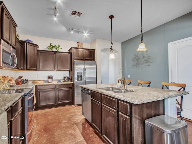 kitchen featuring visible vents, appliances with stainless steel finishes, a kitchen island with sink, dark brown cabinets, and a sink