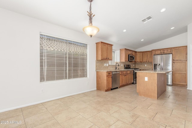 kitchen with stainless steel appliances, vaulted ceiling, visible vents, a sink, and decorative backsplash