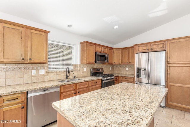kitchen featuring a sink, tasteful backsplash, lofted ceiling, a kitchen island, and appliances with stainless steel finishes