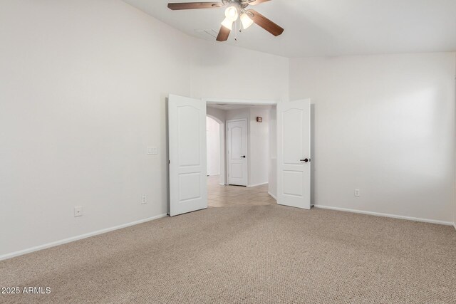 unfurnished room featuring lofted ceiling, ceiling fan, baseboards, and light colored carpet
