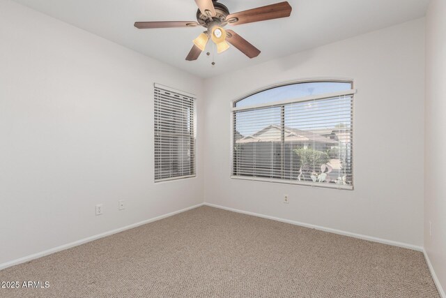 carpeted empty room featuring baseboards and ceiling fan