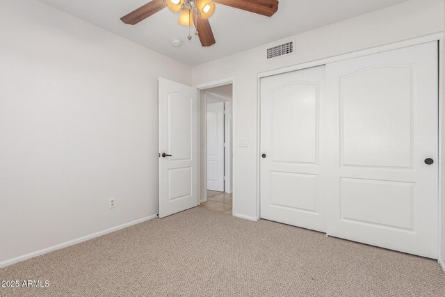 unfurnished bedroom with baseboards, visible vents, light colored carpet, a ceiling fan, and a closet
