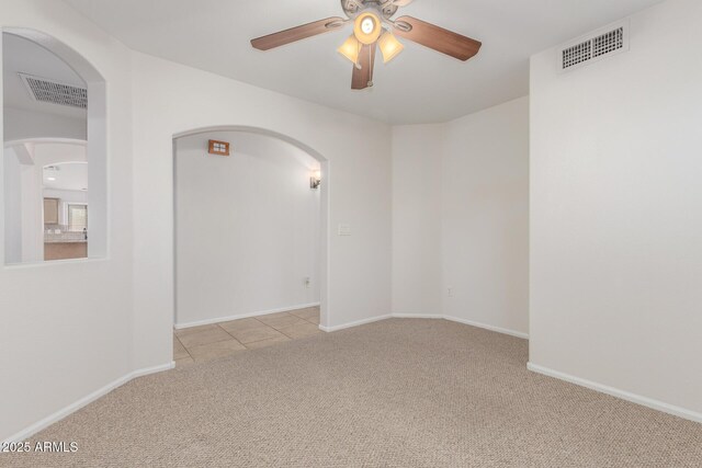 unfurnished room with arched walkways, visible vents, carpet, and ceiling fan