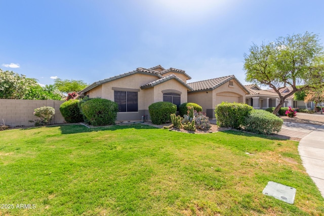 mediterranean / spanish-style home featuring fence, a front lawn, stucco siding, an attached garage, and a tile roof