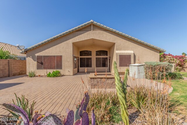 back of property with a tiled roof, fence, stucco siding, and a deck