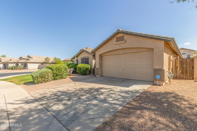 ranch-style home with a tile roof, driveway, an attached garage, fence, and stucco siding