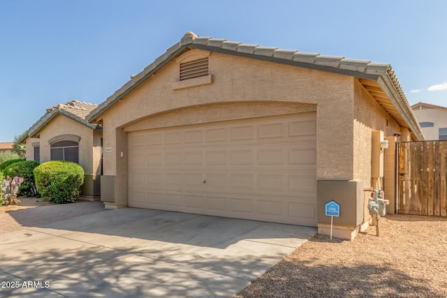 view of front of property featuring an attached garage, a tiled roof, stucco siding, and driveway