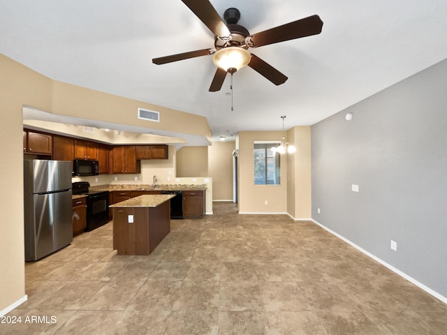 kitchen with a center island, black appliances, ceiling fan with notable chandelier, light stone countertops, and decorative light fixtures