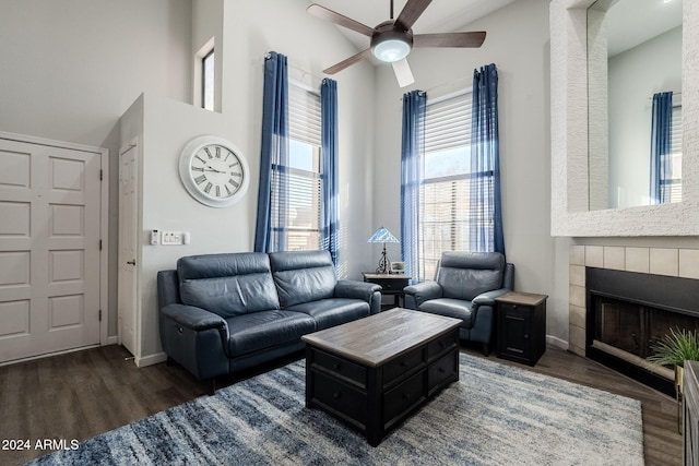 living room featuring a tile fireplace, dark hardwood / wood-style floors, and ceiling fan