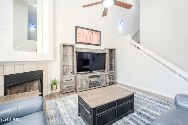 living room with a tile fireplace, hardwood / wood-style flooring, and ceiling fan