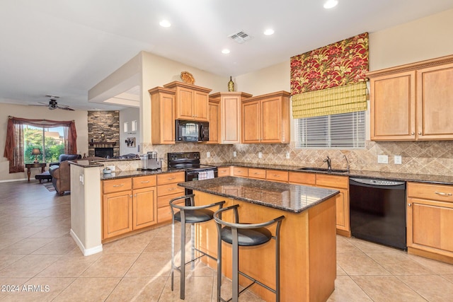 kitchen featuring light tile patterned flooring, black appliances, sink, a kitchen breakfast bar, and kitchen peninsula