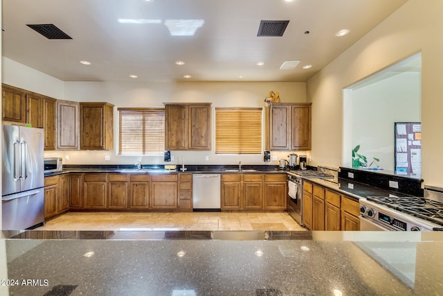 kitchen with stainless steel appliances, kitchen peninsula, sink, and dark stone counters