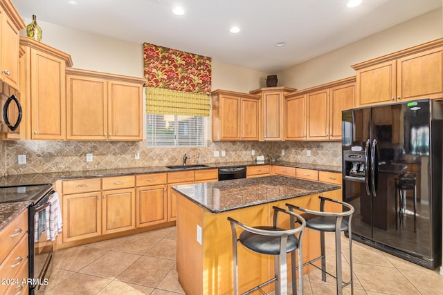 kitchen with light tile patterned flooring, sink, a center island, dark stone counters, and black appliances