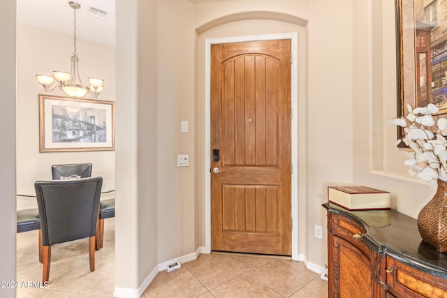 tiled foyer featuring an inviting chandelier