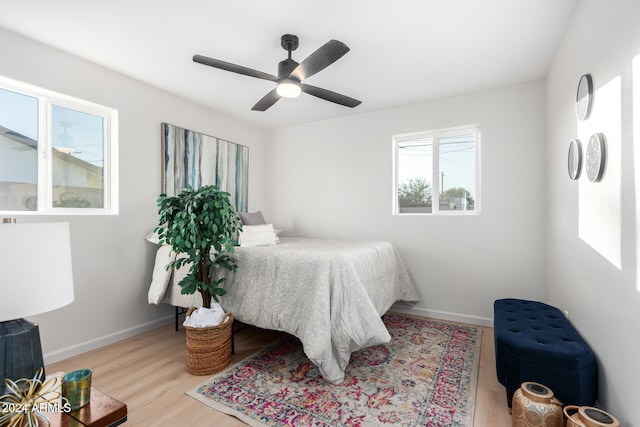 bedroom featuring ceiling fan, multiple windows, and light hardwood / wood-style flooring