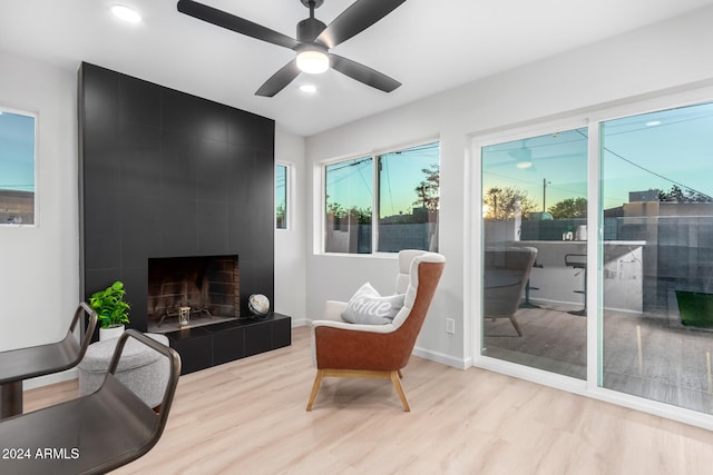 living area with light wood-type flooring, a fireplace, and ceiling fan