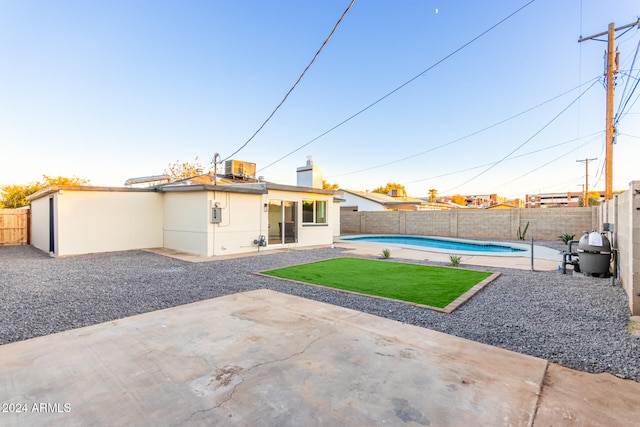 rear view of house with a fenced in pool and a patio