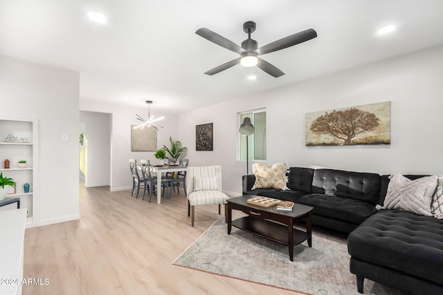 living room featuring light hardwood / wood-style floors and ceiling fan with notable chandelier