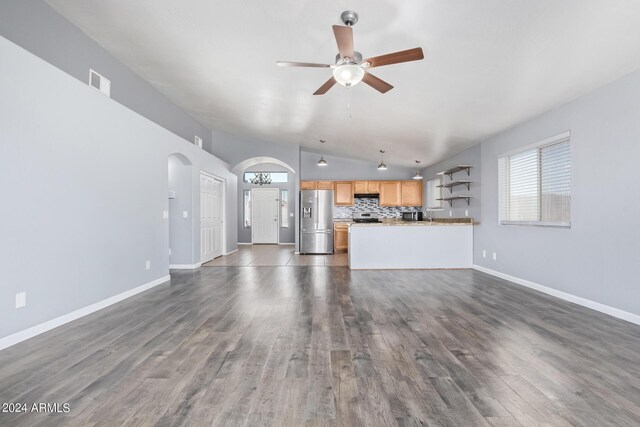 unfurnished living room featuring ceiling fan with notable chandelier, hardwood / wood-style flooring, and lofted ceiling