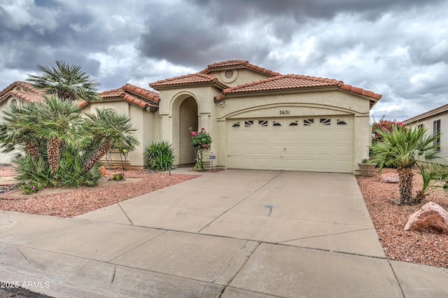 mediterranean / spanish-style house featuring driveway, stucco siding, a tiled roof, and a garage