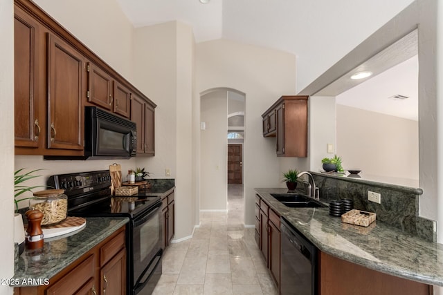 kitchen with black appliances, a sink, arched walkways, dark stone counters, and baseboards
