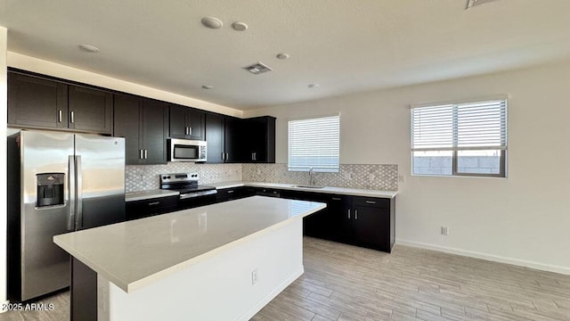 kitchen with visible vents, appliances with stainless steel finishes, a center island, light countertops, and backsplash