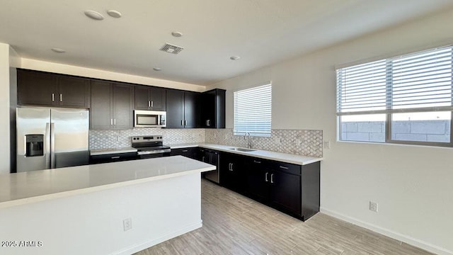 kitchen featuring stainless steel appliances, a sink, visible vents, light countertops, and decorative backsplash