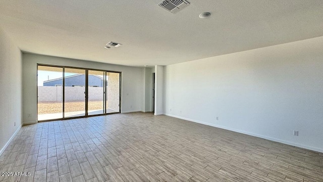 unfurnished room with baseboards, visible vents, a textured ceiling, and light wood finished floors