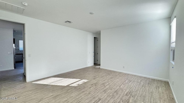 unfurnished room with light wood-style floors, baseboards, and visible vents