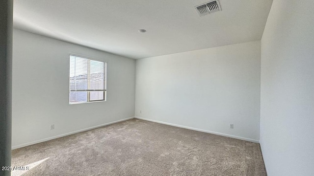 unfurnished room featuring carpet floors, visible vents, and baseboards