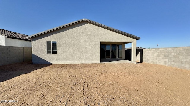 rear view of property with a fenced backyard and stucco siding