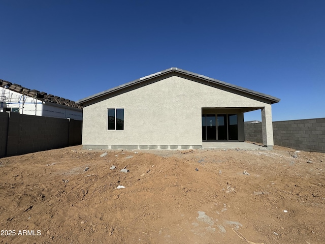 back of property with a fenced backyard and stucco siding