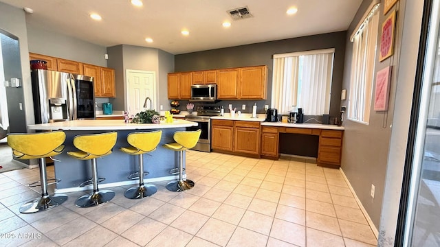 kitchen featuring light tile patterned flooring, a breakfast bar, stainless steel appliances, and a center island