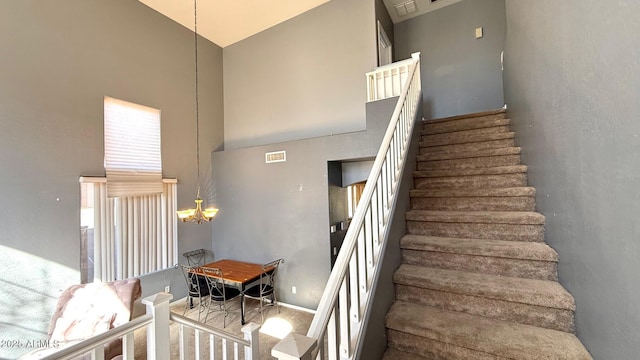 staircase with an inviting chandelier and high vaulted ceiling