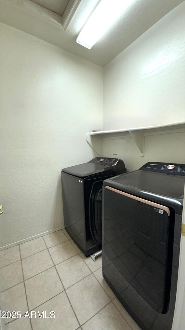 laundry area featuring washer and clothes dryer and light tile patterned flooring