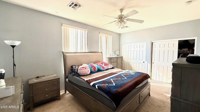 carpeted bedroom with multiple closets and ceiling fan