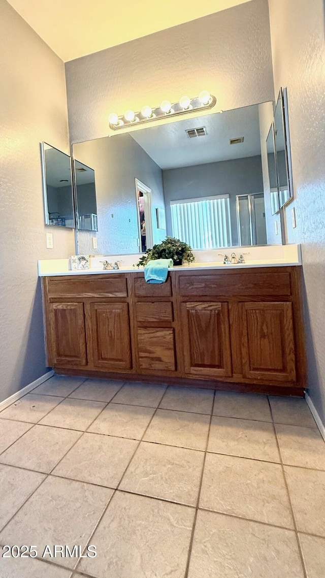 bathroom featuring vanity, an enclosed shower, and tile patterned flooring