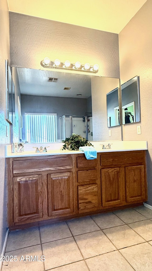 bathroom featuring tile patterned flooring, vanity, and walk in shower